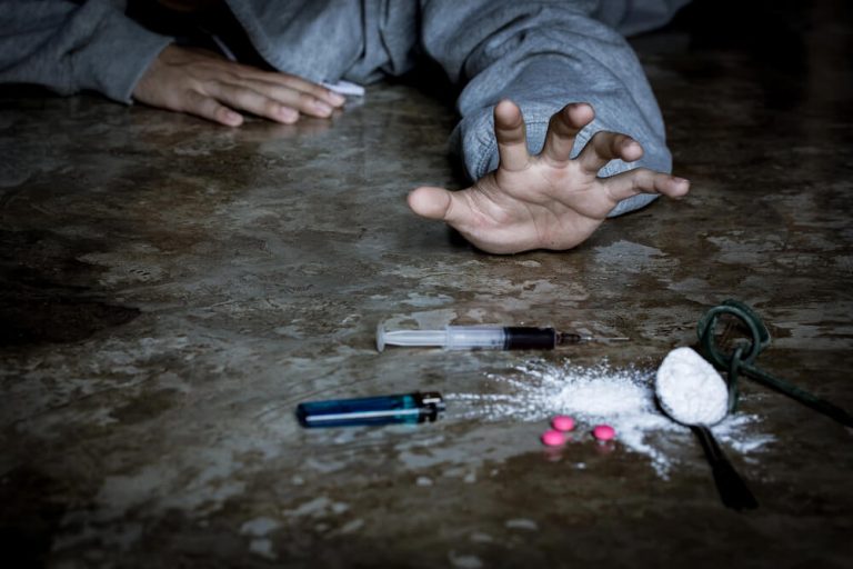 A man is a drug addict with a syringe using drugs lying on the floor. The concept of anti drugs. male drug addict, drug syringe.
