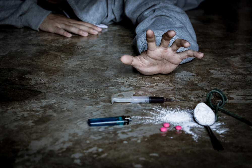 A man is a drug addict with a syringe using drugs lying on the floor. The concept of anti drugs. male drug addict, drug syringe.