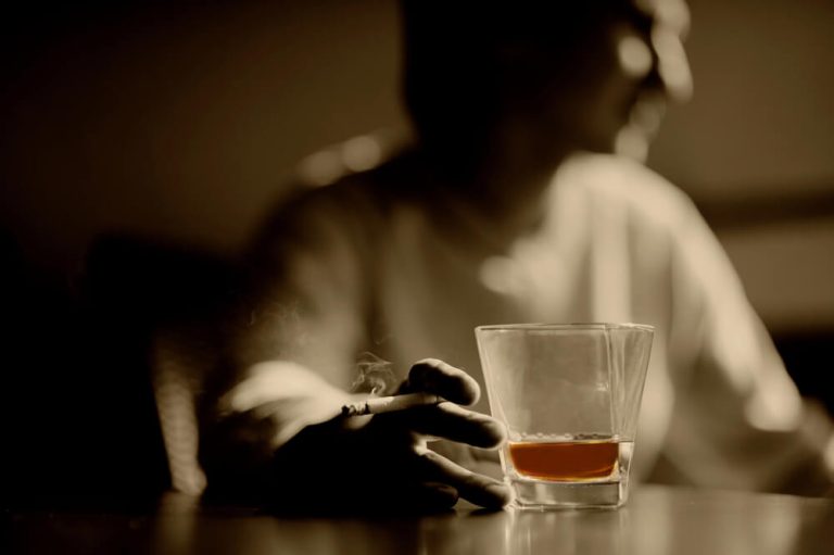 blurred image of a person drinking whisky with a cigarette in his hand